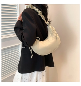 Side view of a beige ruched crescent bag on shoulder with minimalist aesthetic