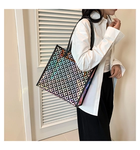 Detail of holographic tote bag with heart patterns and black leather straps on a model