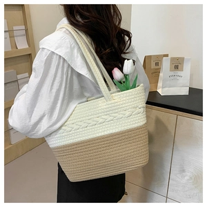 Detail of large straw tote bag featuring cream and tan contrast woven patterns and texture