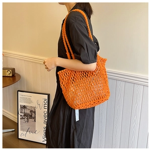 Detail of a bright orange hand-woven mesh shoulder bag with a drawstring inner lining