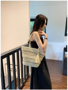 Détail du sac cabas en paille bohème avec texture ondulée et pompon chic