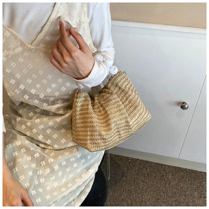 Détail du sac bandoulière en paille avec une poignée à chaîne blanche distinctive