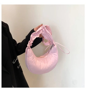 Detailed macro view of the light pink quilted crescent bag with ruffled handle detail