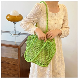 Close-up of green woven handbag with rope texture on a model wearing white lace dress