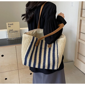 Detail showing beige and navy blue striped woven tote bag with leather shoulder straps