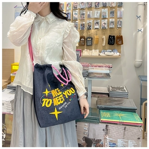 Dettaglio borsa a tracolla in denim scuro con coulisse e ricami a stella colorati