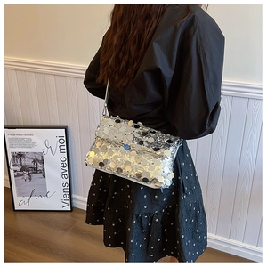 Close-up of silver sequin crossbody bag styled with a black dress for elegant look