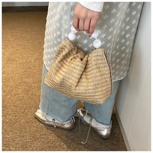 Gros plan d'un sac en paille tressée avec poignée en perles et bandoulière en chaîne