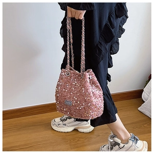 Detail shot of pink sequin bucket bag with metal chain strap worn by a model