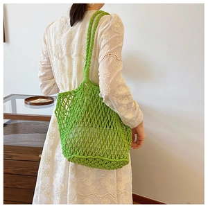 Close-up of green woven mesh tote bag worn on shoulder for summer style