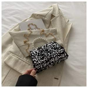 Chic silver and black sequin handbag with pearl handle and golden chain strap on a blazer