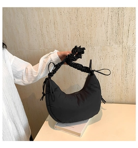 Detailed view of black crescent bag with puffy cloud-style handle and side drawstring detail
