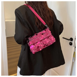 Detail of a bright pink sequined crossbody bag with metallic clasp on a black suit