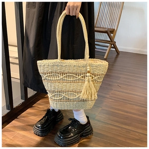 Gros plan détaillé du sac cabas en paille avec des glands décoratifs et perles en bois