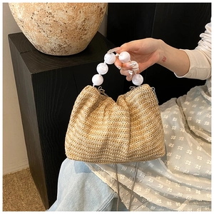 Détail du sac bandoulière en paille d'été avec poignée en perles blanches et fermoir métal