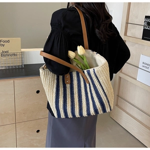 Close-up of a striped woven tote bag with brown leather handles and interior flower detail