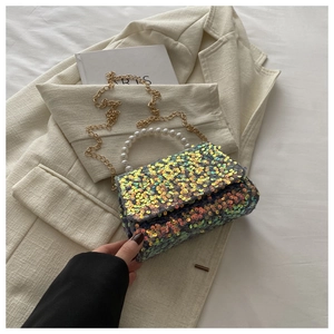 Rainbow sequin crossbody bag with pearl handle and gold chain on beige blazer