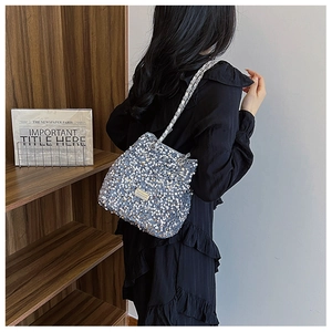 Close-up of stylish silver sequin bucket bag with elegant chain strap worn by a model