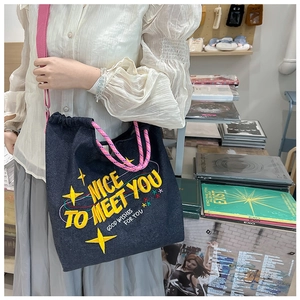 Dettaglio della borsa in denim blu con ricamo a stella gialla e tracolla in tessuto rosa