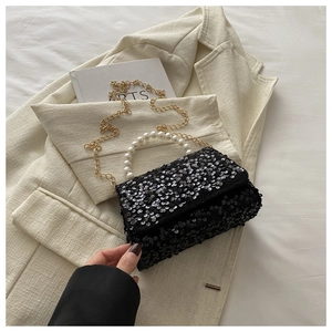 Elegant black sequin handbag featuring a white pearl handle and golden chain strap
