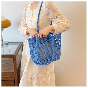 Detail of blue woven shoulder bag with unique openwork mesh design and thick strap
