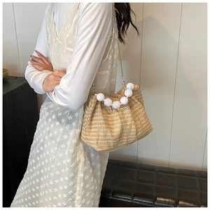 Détail d'un sac bandoulière en paille tressée avec grande poignée en perles et chaîne