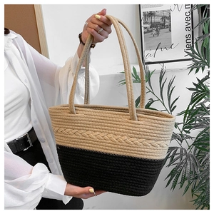Close-up of beige and black woven tote bag texture held by a model in a minimalist room