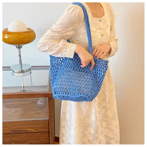 Detail of blue woven tote bag with diamond mesh pattern and thick braided handles