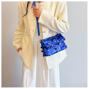 Detail of blue sequined crossbody bag showing sparkling texture on beige blazer outfit