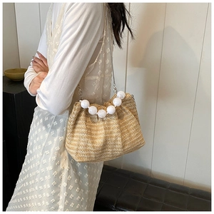 Détail d'un sac bandoulière en paille tissée avec perles élégantes et chaîne argent
