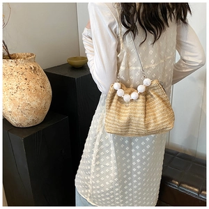 Détail du sac à bandoulière en paille tissée avec poignée à perles et chaîne en argent