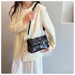 Detail of black sequin crossbody bag showing reflective scales and leather strap