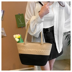Close-up of dual-tone woven straw tote bag with black base and braided detail