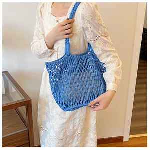 Detail of blue woven mesh handbag texture held by a model in a floral white dress