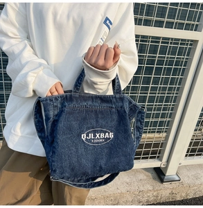 Close-up of washed blue denim handbag featuring white oval embroidery and sturdy straps
