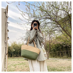 Detail shot of woven texture and green color-block on stylish straw tote handbag