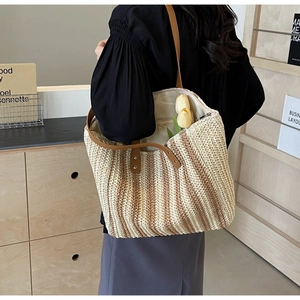 Close-up of a striped woven straw tote bag with brown leather straps and spacious interior