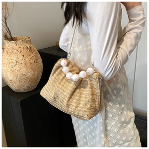 Détail du sac en paille tissée avec poignée à perles blanches et bandoulière argentée