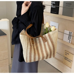 Detail of hand-woven straw tote with vertical stripes and premium brown leather straps