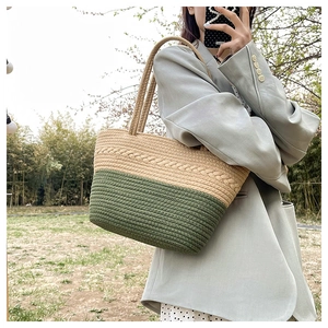 Close-up of woven tote bag with beige and dark green braided patterns in outdoor setting
