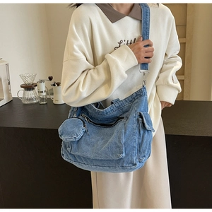 Detail of blue denim canvas crossbody bag with large front pocket and coin pouch