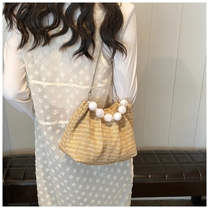 Vue détaillée du sac en paille avec poignée en perles et chaîne d'épaule en métal chic