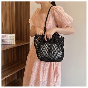 Close-up of black woven mesh bag texture with cotton rope hollow design on a model