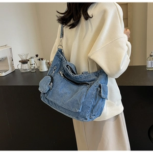 Detail of blue denim tote bag with mini coin purse and adjustable strap in cafe setting