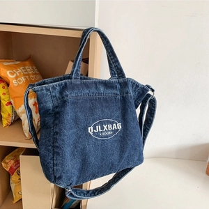 Versatile dark blue denim tote bag with embroidery, featured in a casual wooden setting