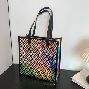 Holographic laser tote bag with heart pattern and black handles on a modern desk
