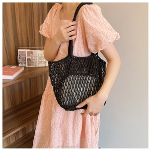 Detail of black hand-woven mesh handbag featuring a white drawstring inner pouch
