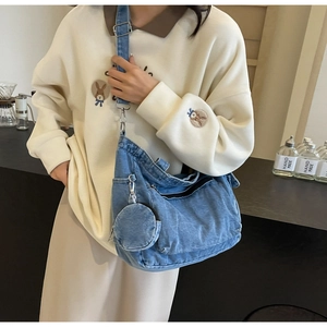 Detail of light blue denim crossbody bag with wide strap and round coin purse