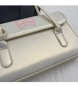 Close-up of pearl white PU leather handbag featuring pink embroidered butterfly detail