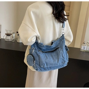 Detail of light blue denim crossbody bag featuring multi-pocket design and small round coin purse